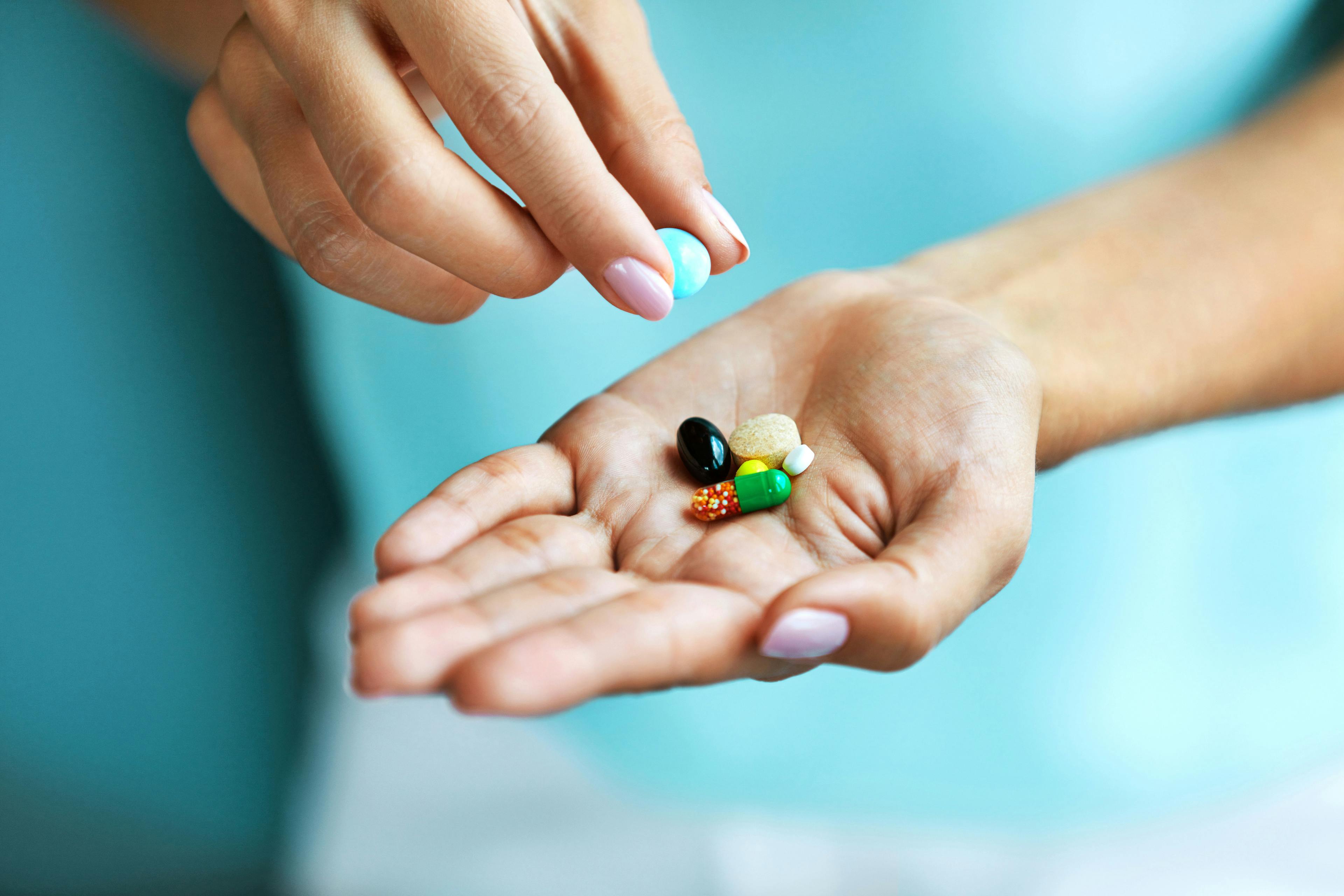 Vitamins And Supplements. Female Hand Holding Colorful Pills | Image Credit: puhhha - stock.adobe.com